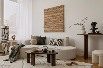 Elegant lounge space with curved sofa, abstract artwork, and a curated console arrangement in...