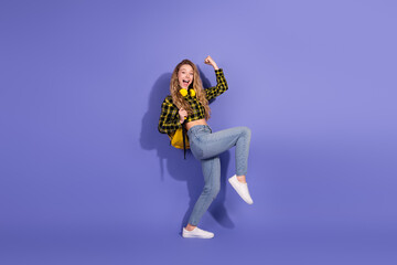 Obraz premium Young woman celebrating joyfully on purple background wearing trendy outfit