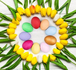 Colored Easter eggs on the desk and tulips bunch