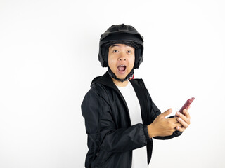 Asian man wearing motorcycle helmet looking to his phone with excited gesture isolated on white background