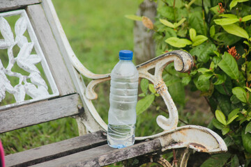 Water plastic bottle on dark brown wooden chair. Discipline to keep public park clean by drop in the bin.	
