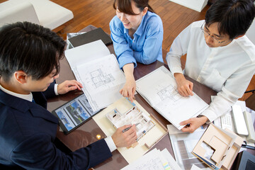 Housing sales: Meeting with the client couple while looking at blueprints in a model room