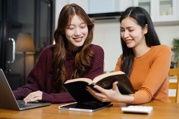 Happy smiling two woman working online sitting in the kitchen.
