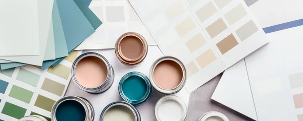 Tiny sample paint cans during house renovation, process of choosing paint for the walls, Mocha Mousse color of the year 2025, color charts on background, banner size © manuta