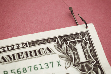one dollar bill pierced by a fishhook