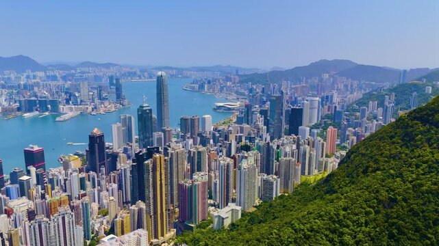 Aerial panoramic top view of forest peak slope and view of high-rise skyscrapers of Hong Kong city