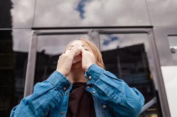 Young boy with a runny nose, holding a tissue. Symptoms of cold, flu, or allergies. Child...