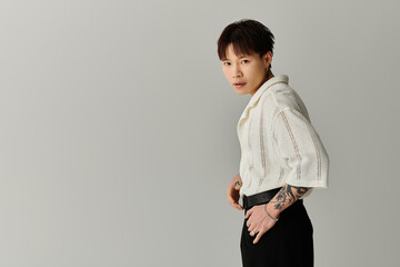 Stylish young Asian man posing confidently against a minimalistic gray backdrop