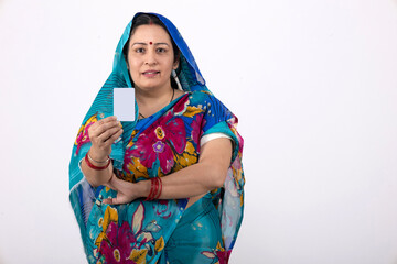 Portrait of an indian rural woman holding Aadhar Card isolated on gray studio background. Rural woman showing Government identity proof on white
