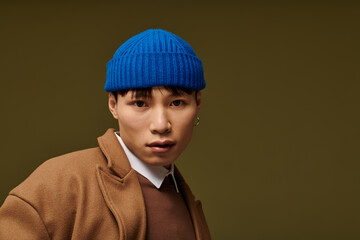 Stylish Asian man in trendy outfit exudes confidence against neutral background