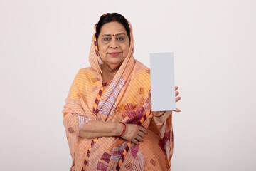 Portrait of an indian rural woman holding Aadhar Card isolated on gray studio background. Rural...