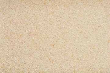 A close-up, overhead shot of a pile of dry, uncooked sushi rice, showcasing its texture and color