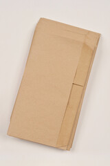 A close-up, angled shot of a stack of brown paper compost bags on a light surface