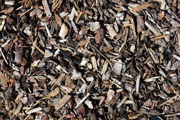 A high-angle, close-up shot of wood chips and bark mulch, showcasing their natural texture and...