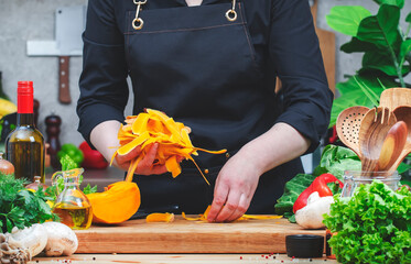 Chef collects pumpkin peels to be processed into compost. Cozy kitchen with wooden table,...