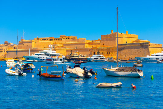 Fort St Angelo in Malta. Fort is framed by modern yachts and boats anchored in the harbor, creating a striking blend of old-world charm and contemporary maritime activity