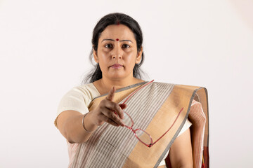 Portrait of an indian school teacher scolding with holding scale on white studio background
