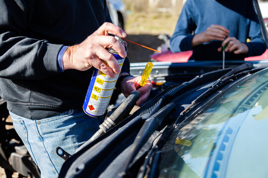 Man using grease to pull apart smashed car for parts