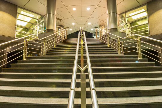 Looking up a staircase with stainless steel railings leading into a modern building