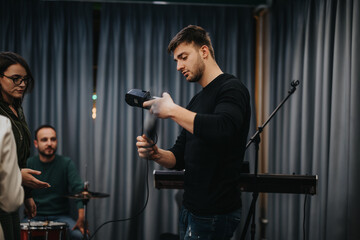 A group of people in a rehearsal room preparing and readying musical equipment and instruments.