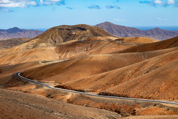 Winding road through arid hills of Fuerteventura's volcanic terrain.