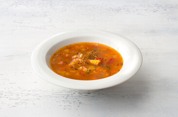 Homemade vegetable soup with pumpkin, bell pepper, tomato, and buckwheat on a light grey table. Delicious vegan comfort food