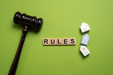 Blocks with the word Rules, a judge's gavel and miniature wooden houses. laws, regulations, and...