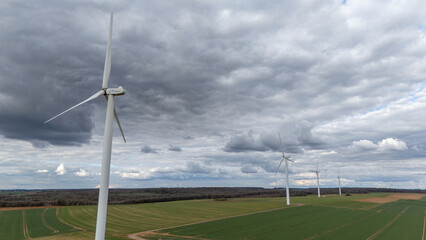 Des éoliennes  vues en hauteur avec un drone, le ciel est très nuageux et gris, avec quelques...