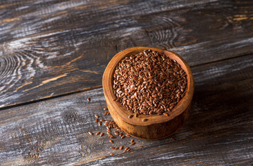 Brown flax seeds in a rustic wooden bowl on a wooden table with copy space