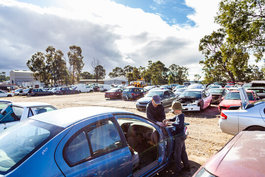 Father and son working a wreckers pulling apart old car for parts