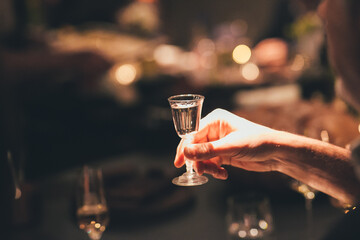 A person is holding a shot glass of wine, showing enjoyment