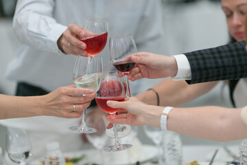 A gathering of individuals is raising their wine glasses in a toast at a table