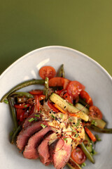Hot salad with veal, zucchini, tomatoes, asparagus and cheese