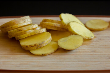  raw potato slices on wooden cutting board close-up