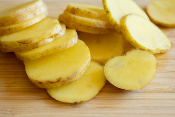  raw potato slices on wooden cutting board close-up