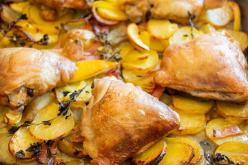 roasted chicken thigh with potatoes, lemons, and shallot onions in a tray close-up