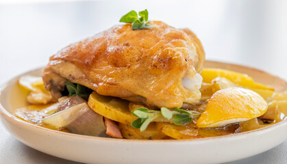 roasted chicken thigh with potatoes, lemons, and shallot onions in a dish close-up