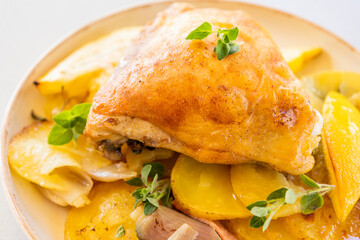 roasted chicken thigh with potatoes, lemons, and shallot onions in a dish close-up