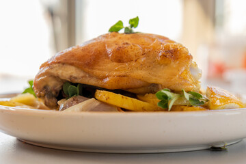 roasted chicken thigh with potatoes, lemons, and shallot onions in a dish close-up