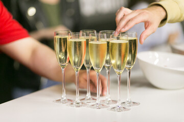 A person extends their hand towards a glass of champagne on a table