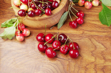 Red cherries in a wooden bowl on a kitchen table.