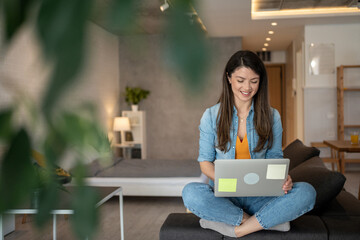 Happy freelancer working from home using laptop on sofa