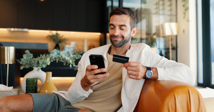 Credit card, mobile and happy man with payment in home for online shopping, internet banking or purchase. Phone, debit and person with digital money in living room for ecommerce, finance or deposit