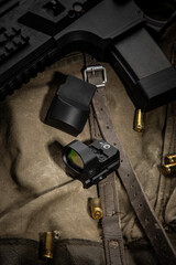 A detailed setup featuring a firearm, ammunition, and red dot optics, displayed on a fabric...