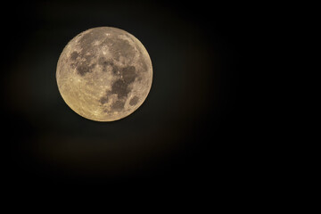 The full moon at west begins to be illuminated by the light of dawn, over the eastern Andean mountains of central Colombia.