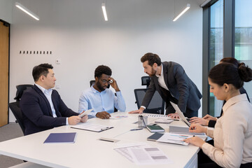 An angry businessman berates his team in a modern office boardroom, creating a tense atmosphere...