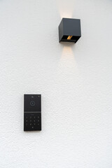 Modern Smart Doorbell and Wall Lamp on White Textured Wall