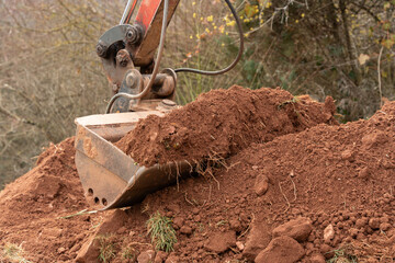 Close-up of the excavator bucket picking up clay soil with stones in the bucket