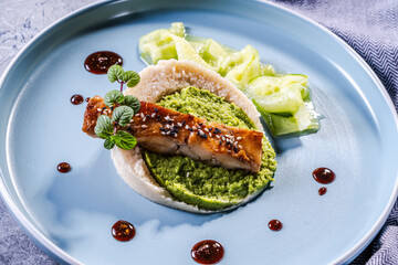 Cod fillet fried with spinach and broccoli and cauliflower puree sauce on a blue plate. The concept of healthy and dietary nutrition. Restaurant serving of the dish.