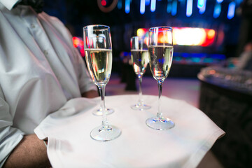 A man holds a silver tray with two elegant glasses of champagne